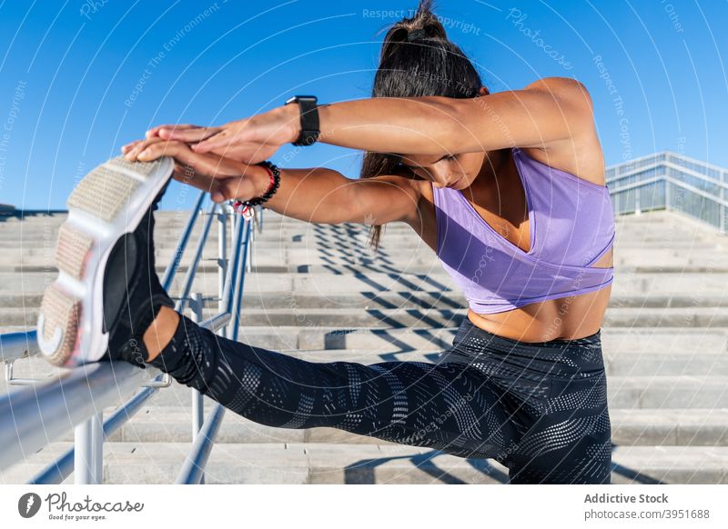 Slim woman stretching legs during training sportswoman athlete city warm up forward bend flexible exercise female sportswear railing healthy wellness fitness