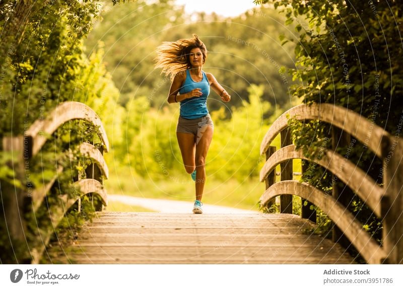 Slim woman running along wooden path in park - a Royalty Free Stock Photo  from Photocase