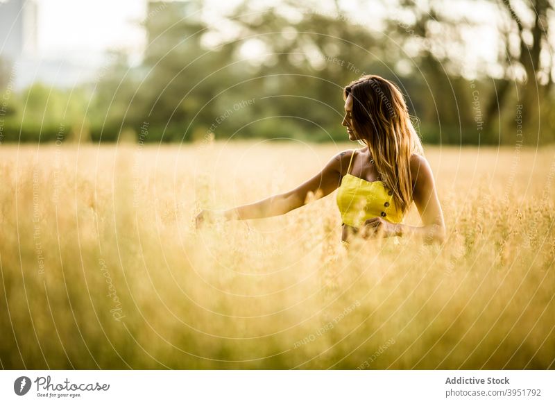 Woman walking in field in summer woman tranquil carefree touch grass park meadow female salburua vitoria gasteiz spain nature weekend calm harmony outfit yellow