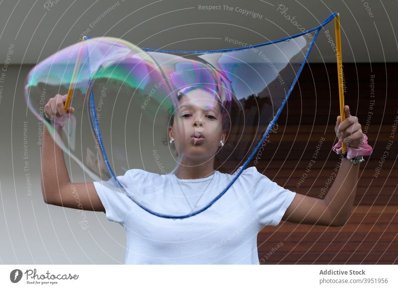 Excited black teen girl playing with colorful soap bubbles woman having fun cheerful excited joy playful enjoy positive happy female young african american