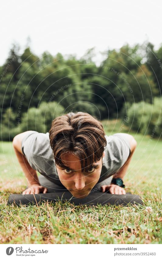 Young man doing push-ups outside on grass during his calisthenics workout active activity athlete athletic body bodybuilder bodybuilding care caucasian cross