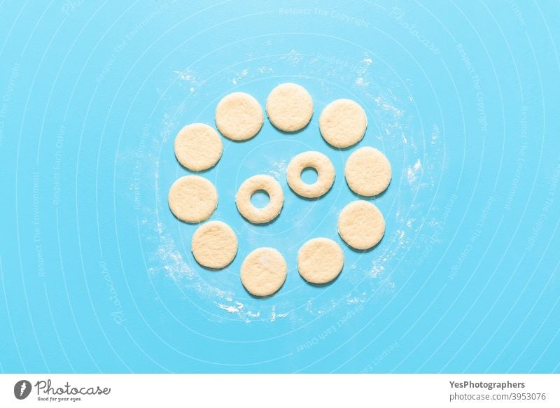 Making doughnuts flat lay. Uncooked raw dough prepared for donuts aligned american baking blue background breakfast cake calories circle shape comfort food