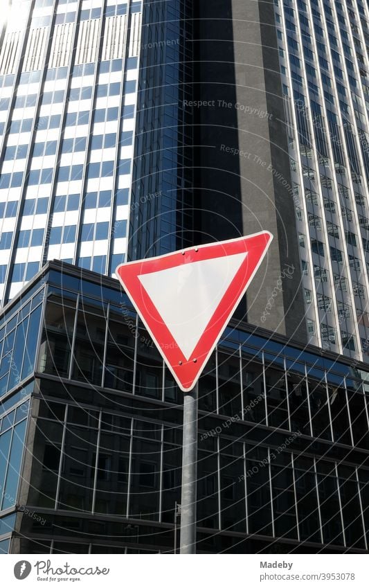 Triangular traffic sign grant right of way in the Neue Mainzer Straße in front of the Eurotower in summer at sunshine in Frankfurt am Main in Hesse Road sign