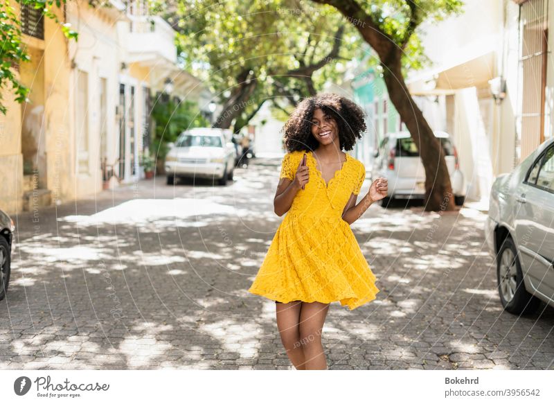 Young black woman with curly hair, in yellow dress and with styles, attitude, laughing, happy individuality ethnicity skin smiling hairstyle message afro