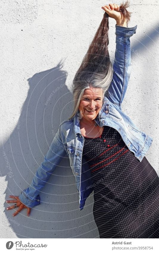 An older woman stretches her very long grey hair upwards laughing Woman Long long hairs age Gray-haired Senior citizen fun Joy Funny pleased Laughter gray hair