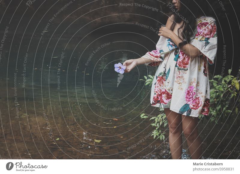 A woman on a pond holding a flower showing concept of wellness in nature, mindfulness and mental wellbeing femininity elegance sensual nature and wellness