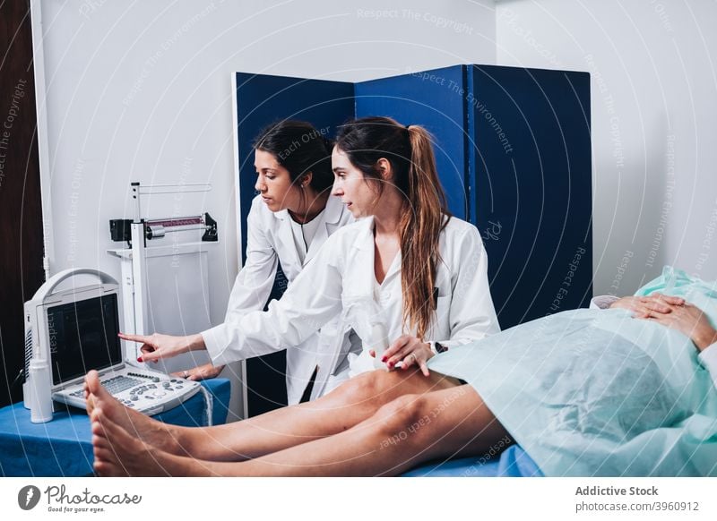 Doctors are making an ultrasound to the legs of a patient CrotoChic analysis analyzing anatomy bone checking clinic coat colleagues consultant cream diagnosis
