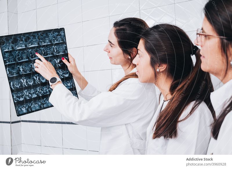 Doctor in uniform showing an X-ray to two other doctors CrotoChic analysis analyzing anatomy bone checking clinic coat colleagues consultant diagnosis