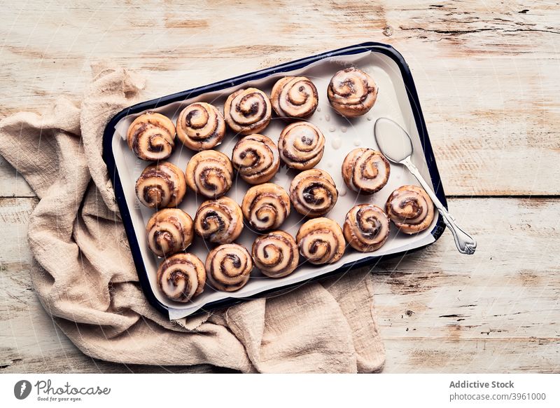 Tasty cinnamon buns on tray on table roll baked bakery glaze frosting dessert delicious food sweet gourmet pastry wooden nutrition culinary row cuisine many