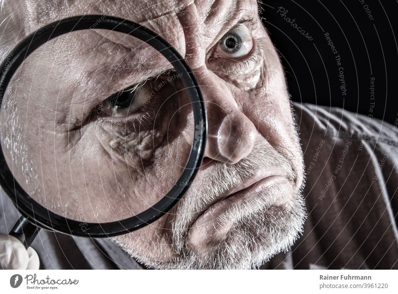 a man looks skeptically through a large magnifying glass Man portrait Magnifying glass see Observe Face Looking Eyes Human being Colour photo