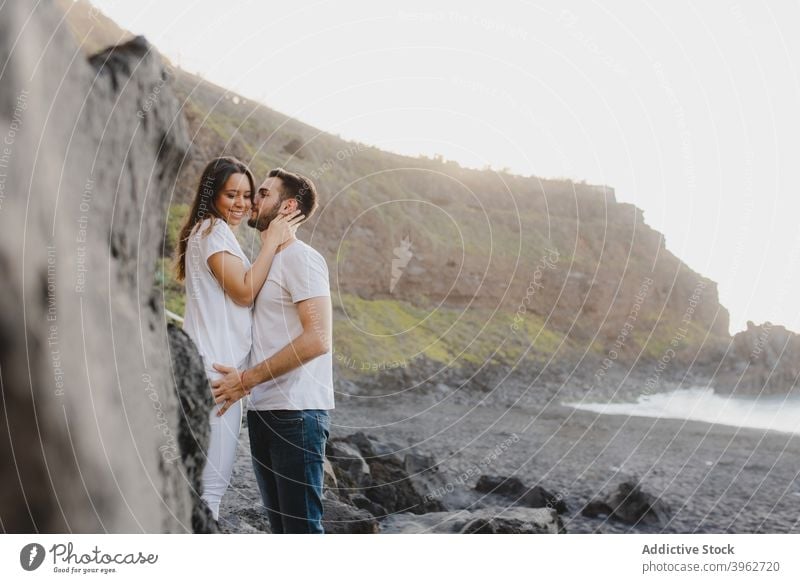 Loving couple embracing on rocky seashore romantic love embrace kiss coast beach together fondness happy young tenerife island canary spain relationship