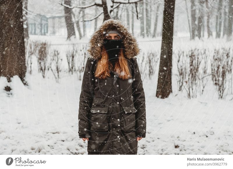 woman with face mask standing outdoors in snow adult alone attractive beautiful black brunette cold confident coronavirus covid-19 cute fashion female forest