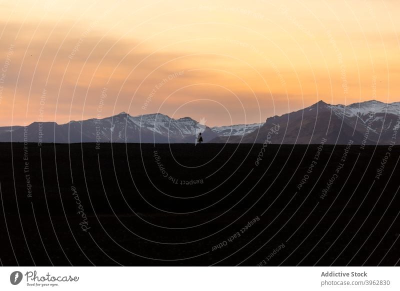 Traveler standing in mountains at sunset traveler silhouette winter sky highland admire landscape sundown iceland explorer terrain cold scenic snow nature