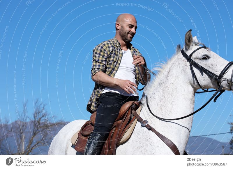Young guy in casual outfit riding white horse on sandy ground equestrian equine horizontal obedient ranch creature dressage horseback jockey male mammal mare