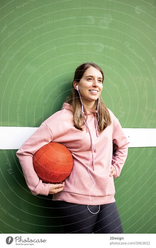 young long haired woman holding a basket ball against green wall sport person basketball fitness training athlete female girl player exercise healthy lifestyle