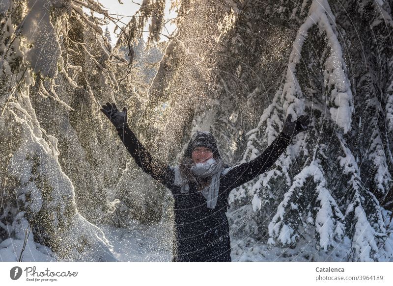 The young woman is happy about the shower of snow that falls from the firs and raises her arms coniferous Forest Weather Snow Winter chill Day daylight Tree