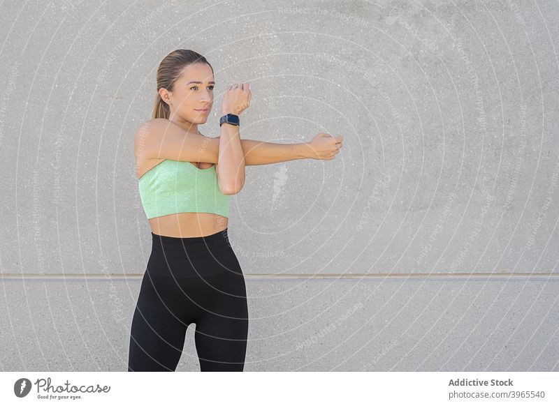 Slim woman stretching arms before workout - a Royalty Free Stock