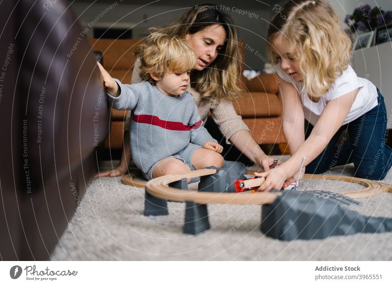Mother with kids playing with toy roadway mother together car at home child activity parent lifestyle love childhood relationship motherhood childcare