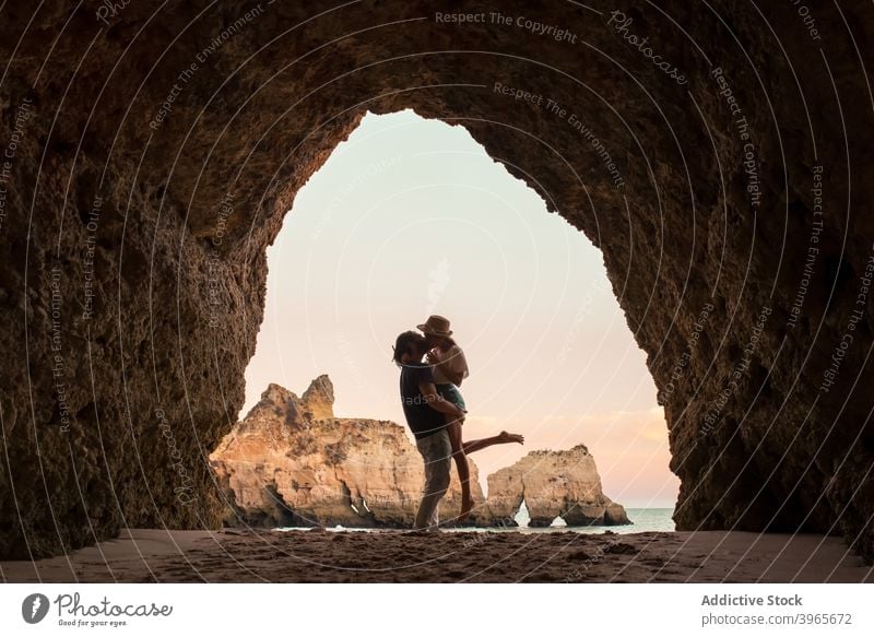 Anonymous couple kissing in cave entrance hug sea love evening man woman algarve portugal embrace romantic relationship ocean together boyfriend girlfriend