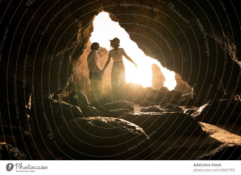Happy couple kissing in cave entrance sea love evening man holding hands woman algarve portugal smile embrace romantic relationship ocean together boyfriend