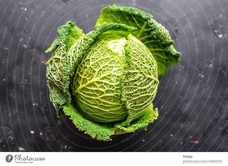 A raw savoy cabbage on a black background. Top view Savoy cabbage Cabbage Raw Green Vegetable Food Nutrition Vegetarian diet Healthy Organic produce