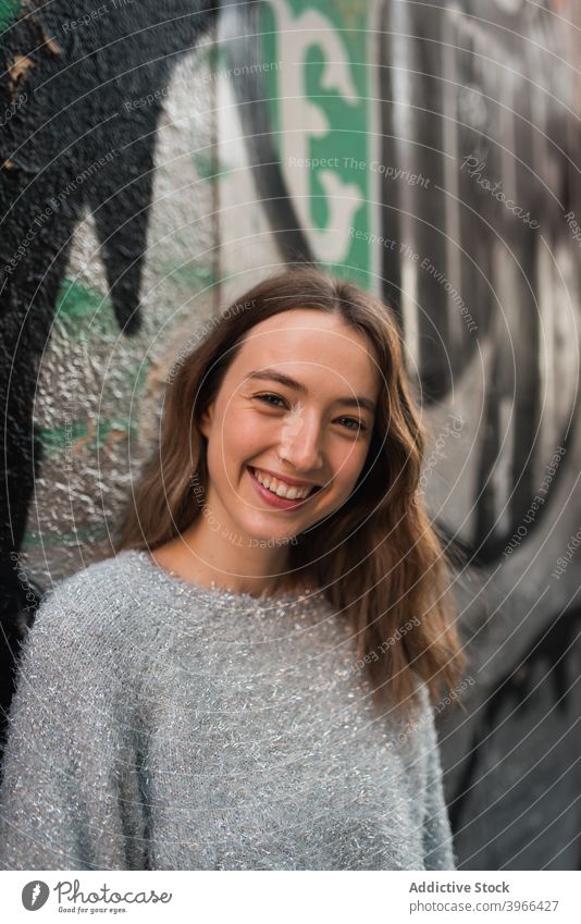 Delighted woman near graffiti wall in city urban street cheerful cool young street art female creative colorful style modern happy area smile trendy optimist