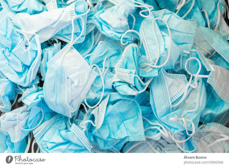 Texture of wrinkled protective face masks, discarded dirty trash. used isolated disposable plastic color blue strips white contamination pollution problem