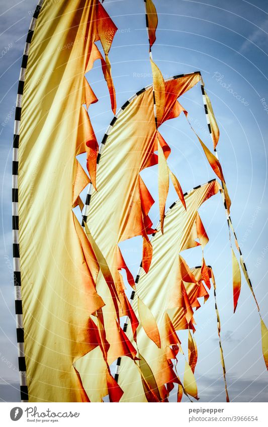 Beach flag flags like fire Beachflag Flag Wind Flagpole Judder Blow Sky Exterior shot Deserted Beautiful weather Fire Yellow Red Clouds Blue sky waving flags