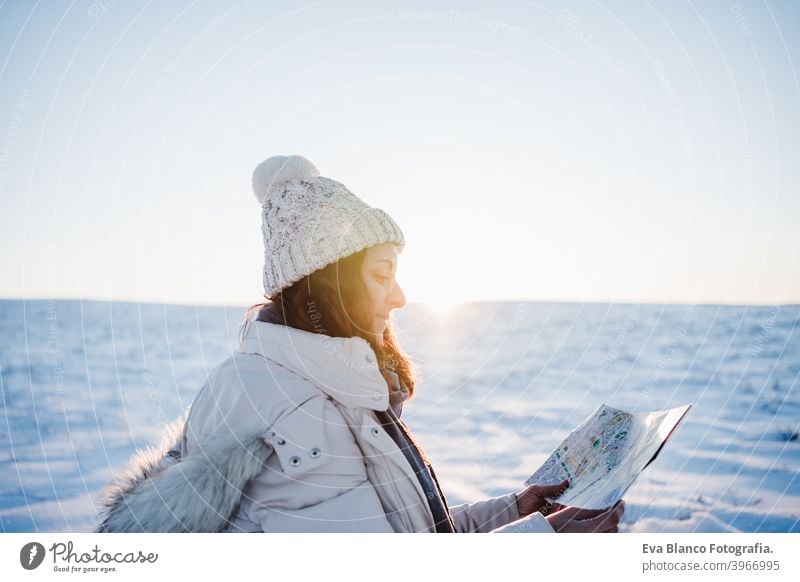 beautiful young woman at sunset in snowy mountain reading a map. Travel, Nature and technology concept. winter season hiking cold covered caucasian forest