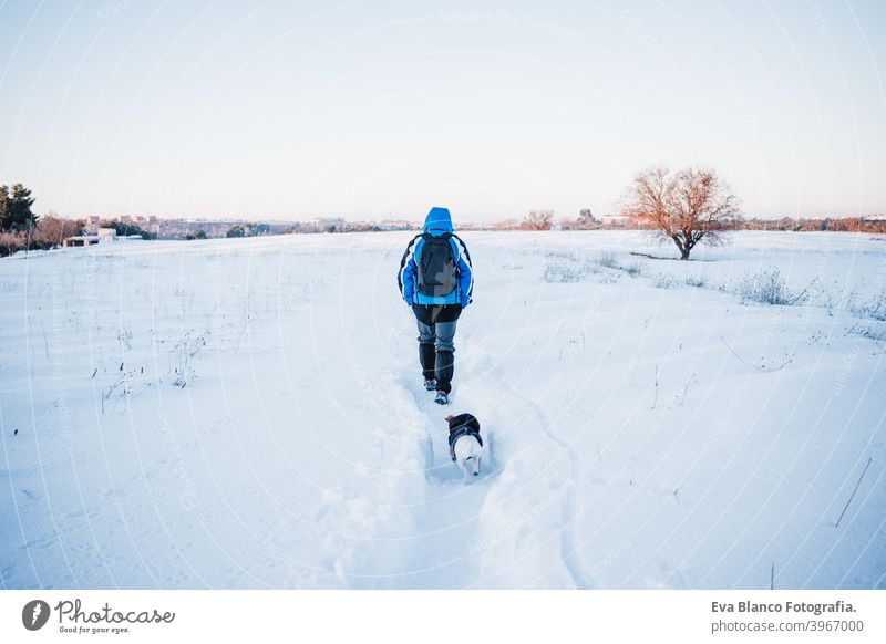 back view of happy man in snowy mountain at sunset. Travel and sport outdoors concept. Winter season dog jack russell travel owner pet love together hiking