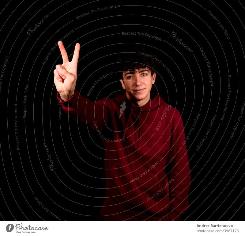 Attractive young man making the victory symbol on a black studio background happy caucasian photogenic gesture shirt beautiful positive adult face peace