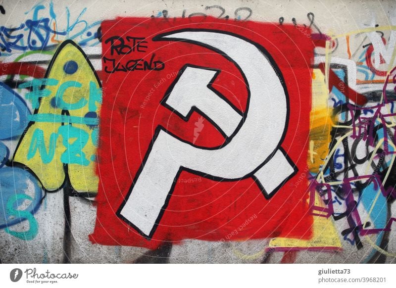 Graffiti | Hammer and sickle sprayed with white paint on a red background on a wall and supplemented with the words Red Youth graffiti Graph hammer and sickle