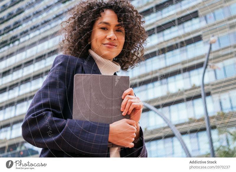 Businesswoman holding tablet on city street businesswoman using urban young formal browsing digital contemporary positive ethnic female curly hair modern