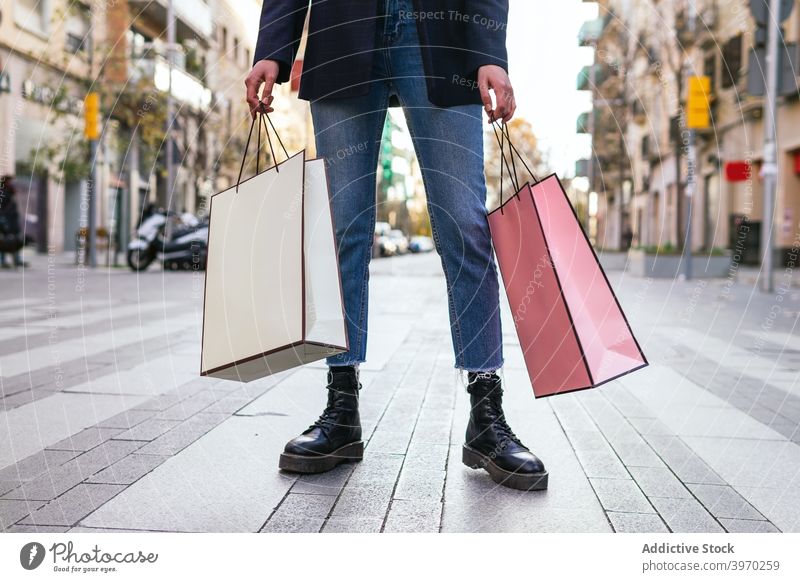 Crop woman with shopping bags in street paper bag city buyer shopper consumerism customer shopaholic female purchase sale retail discount trendy style apparel