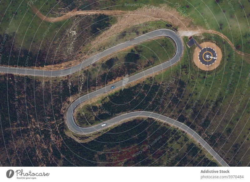 Modern round helipad in green suburbs road curve mountain landscape highland picturesque terrain nature scenery scenic hill valley idyllic destination