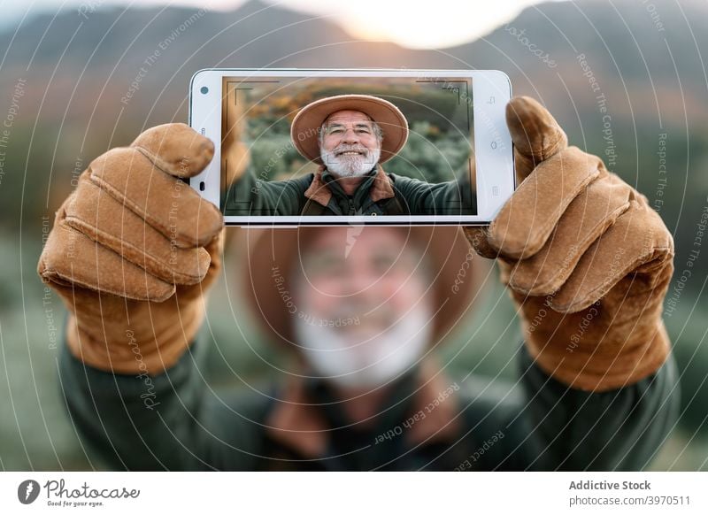Elderly man taking self portrait on smartphone in nature traveler photography selfie cheerful senior mountain display vacation male caceres extremadura spain