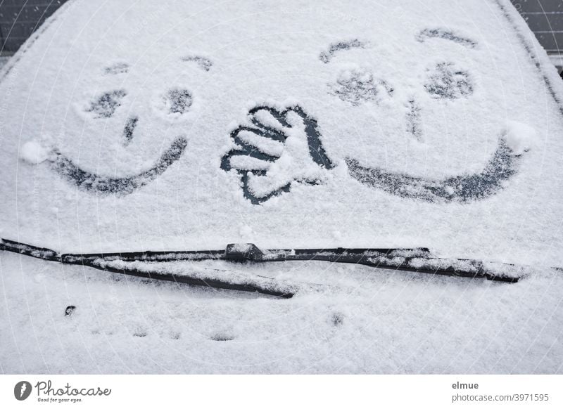 two faces and a hand can be seen on the windshield of a snowy car / winter fun Snow Windscreen wiper Hand Painting (action, artwork) scratch free snowed over