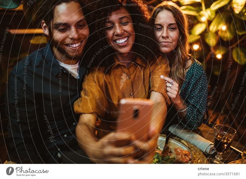 mixed race group of young adult friends taking selfie with phone at party Candid Happiness Smartphone Smiling Young Adult african american african ethnicity