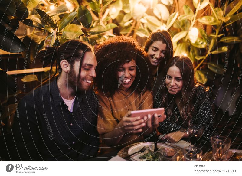 Group of young adult friends looking at phone having fun at party Candid Happiness Smartphone Smiling Young Adult african american african ethnicity caucasian