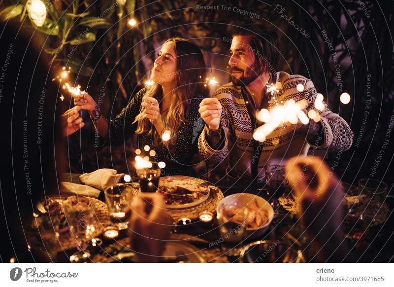 Young adult couple celebrating with sparklers at dinner party together 4th of july Candid Dating Happiness Heterosexual Couple People Smiling Young Adult