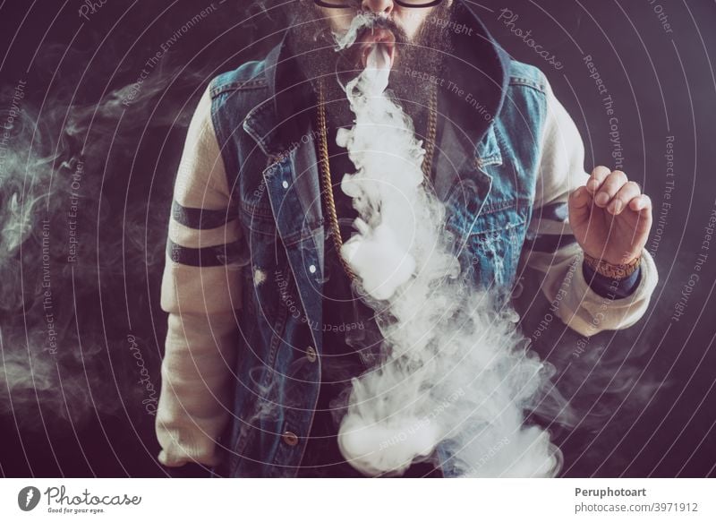 Young man with beard throwing a cloud of steam. Black background. Vaping an electronic cigarette vape vaping smoke adult cool lifestyle person smoker habit