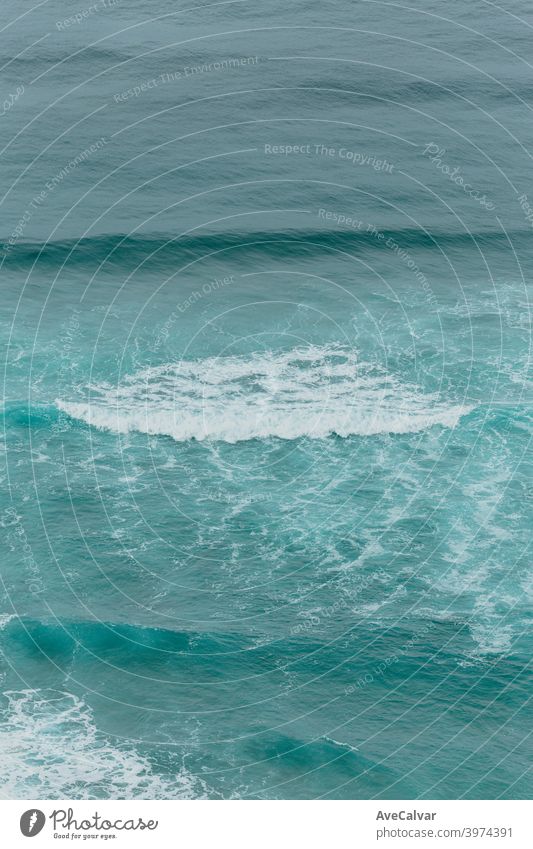 Aerial view of the ocean with the waves and re rocks during a bright day, relaxing scene on blue tones oceans copy-space meditation calmness textures peace awe