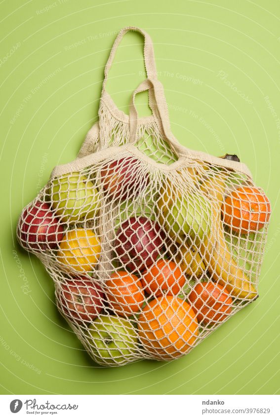 ripe fresh fruits in a textile string bag on a green background orange apple banana concept cotton eco ecological ecology food friendly grocery harvest health