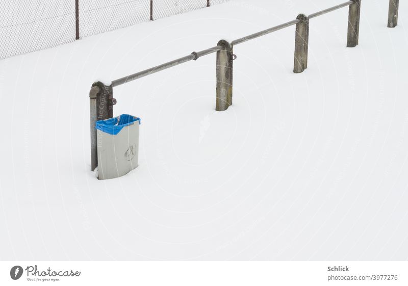 Trash can with blue plastic bag on the edge of a sports field protected from the high snow and corona virus from annoying users rubbish bin Snow