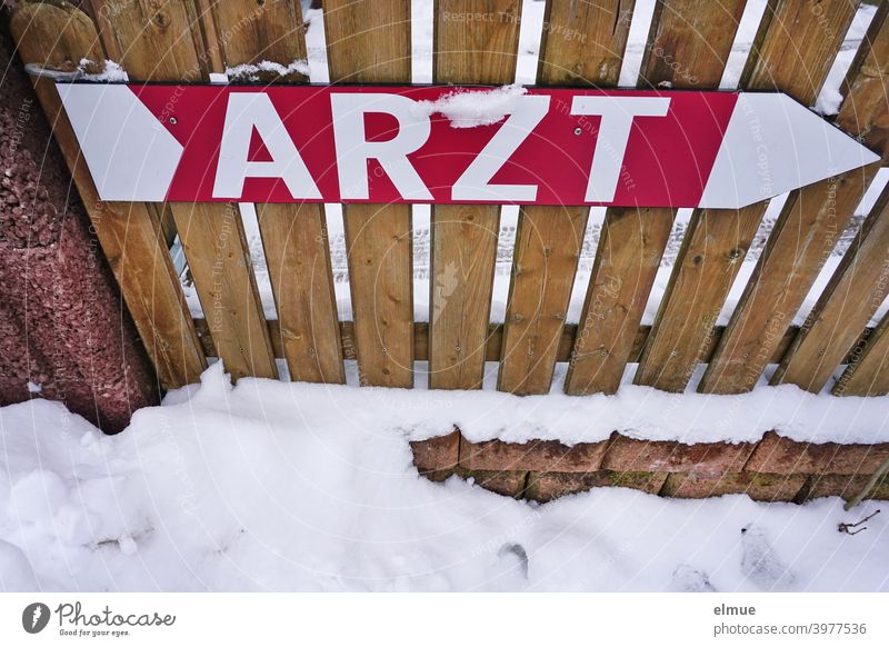 Sign as a large arrow and with the inscription "ARZT" in block letters is attached to a wooden picket fence / medical help / orientation sign Doctor Clue Arrow