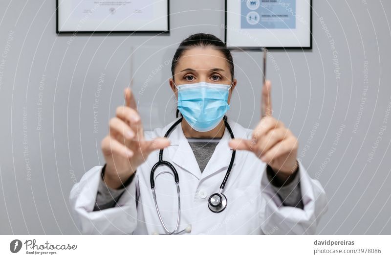 Female doctor holding a transparent tablet futuristic showing woman covid-19 technology glass screen people white coat health care person digital looking camera