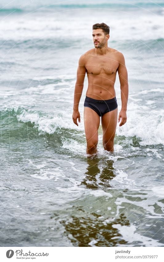 Young man on the rocks by the beach wearing underwear Stock Photo