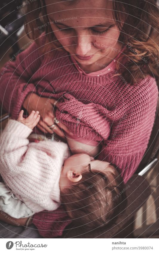 Young woman breastfeeding her baby breast feeding mom motherhood family exclusive mama infancy newborn pink warm cozy natural real life realistic love
