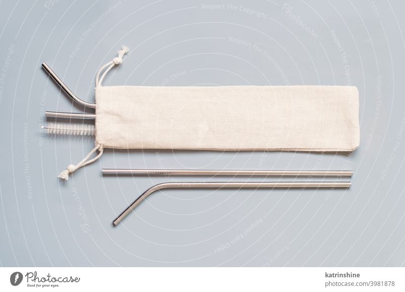 Reusable stainless steel straws and cleaning brush with cream cotton bag on grey background. top view mockup Eco friendly lifestyle concept monochrome Objects
