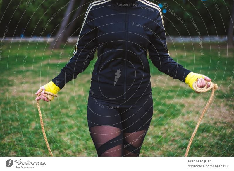 Outdoor shot of active brunette woman exercises with fitness ball poses at  green grass, dressed in active wear, enjoys sunny day and fresh air in  park, keeps fit, makes gymnastics exercises. 